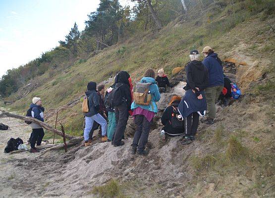 Studenci geografii przy klifie w trakcie pobierania próbek osadów