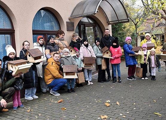 Grupowe zdjęcie przed budynkiem Błękitnej Szkoły; uczestnicy z karmnikami