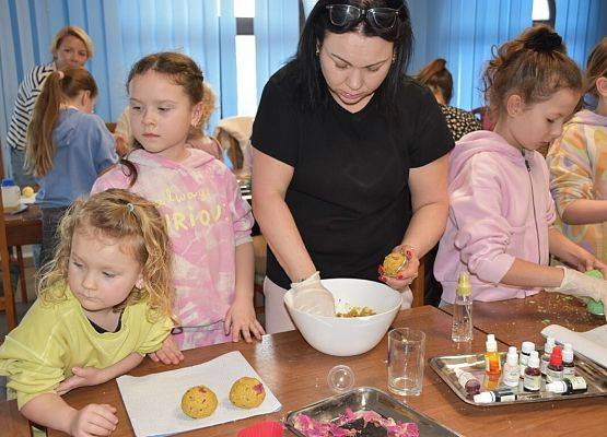 Uczestniczki wkładają żółtą masę do foremek w kształcie kuli