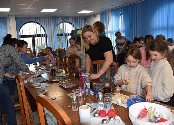 Liczna grupa na sali. Na stolikach liczne akcesoria do wykonania kul do kąpieli i tabliczek zapachowych