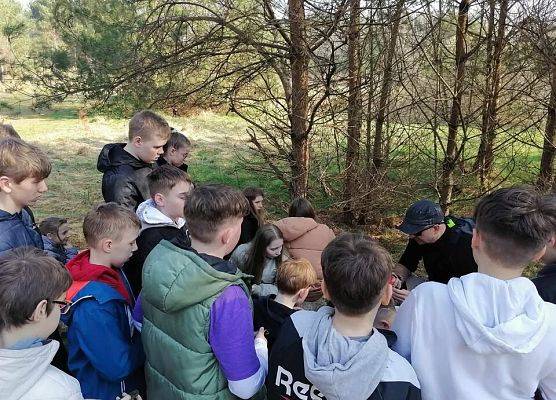 grupa ok 20 uczniów stoi wokół edukatora.