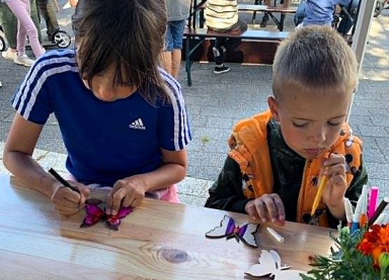 dwie dziewczynki przy stoliku kolorują pisakami 10 cm.modele motyli z drewnianej sklejki o wielkośći ok